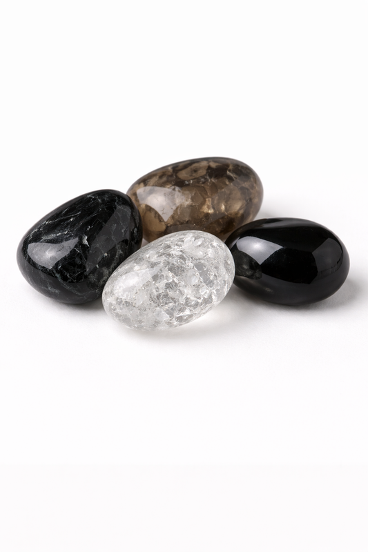 Four polished gemstones in black, clear, and brown on a white background