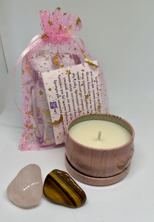 Candle in a decorative container with two stones and a pink gift bag on a white background