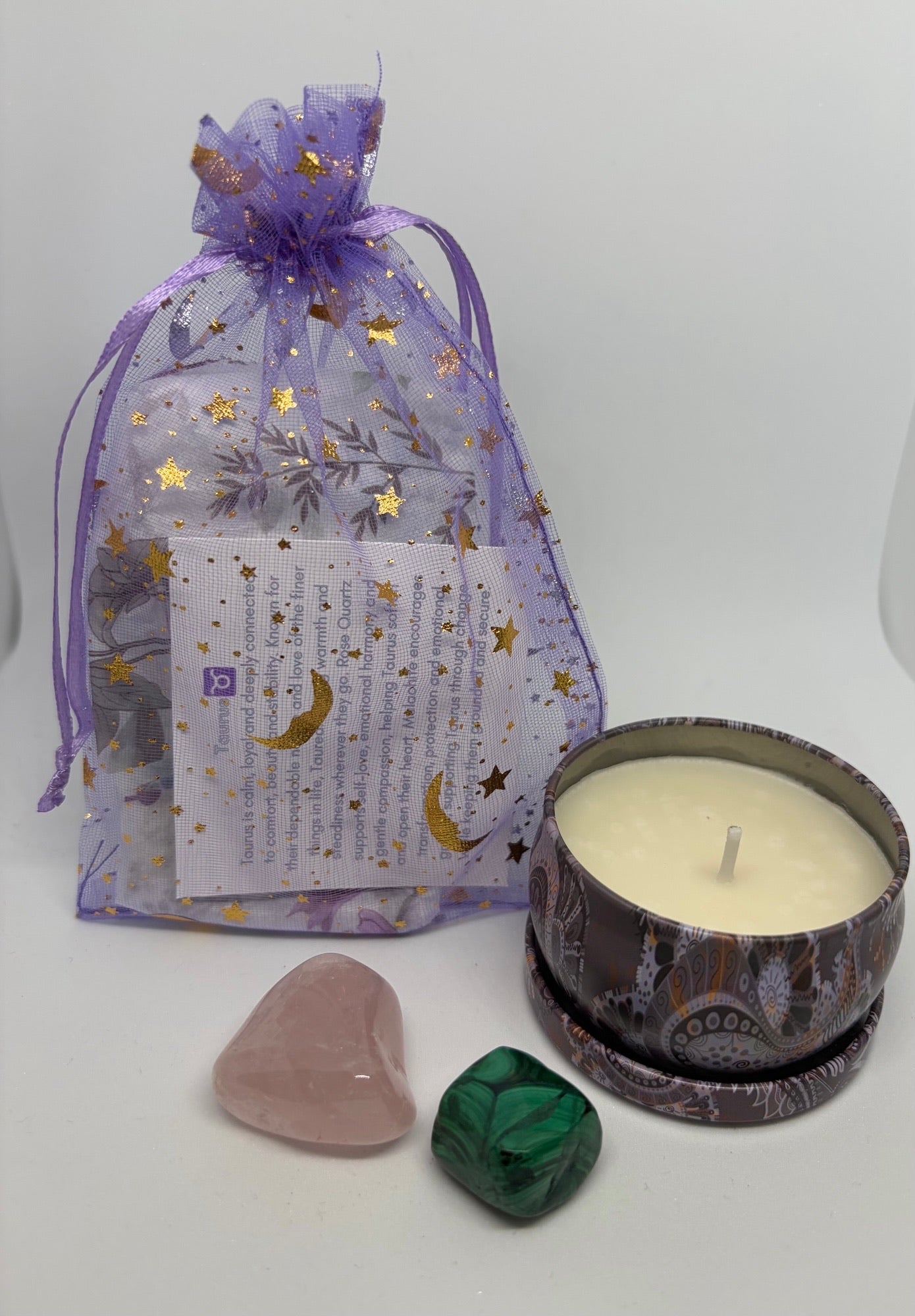 Purple organza gift bag with a rose quartz crystal and malachite crystal with a soy wax candle in a tin